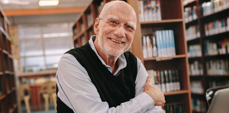 Senior man sitting inside a library